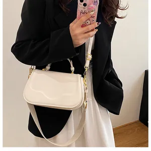 Détails d'un sac à main crème en similicuir avec surpiqûres et bandoulière large en tissu