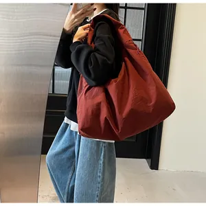Dettaglio della grande borsa tote in nylon rosso mattone con trama morbida e design ampio