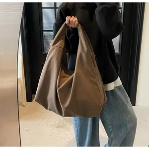 Dettaglio di una grande borsa tote in nylon marrone caffè con pieghe morbide e texture lucida