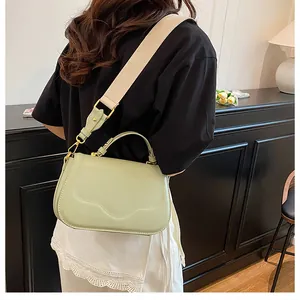 Détail du sac selle vert menthe avec bandoulière beige et garniture dorée sur modèle