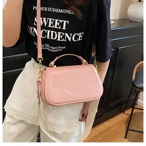 Sac à bandoulière rose sur mannequin avec large sangle tissée et boucle en métal chic