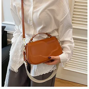 Détail du sac à main marron caramel avec rabat ondulé et deux bandoulières élégantes