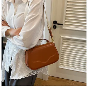 Détail du sac à main marron avec large bandoulière crème porté par un mannequin