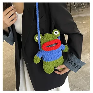 Detail of a handmade green crochet frog crossbody bag with big red lips on a black blazer