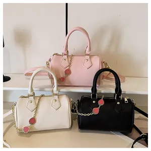 Three boston handbags in pink, white and black with strawberry charms on display