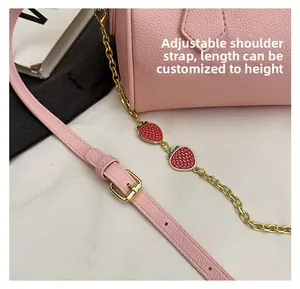 Detail of pink lychee leather bag with strawberry charms and adjustable strap