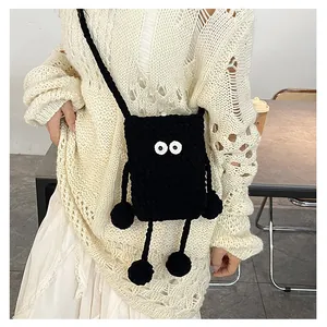 Detail of a handmade black knitted crossbody monster bag with large expressive eyes