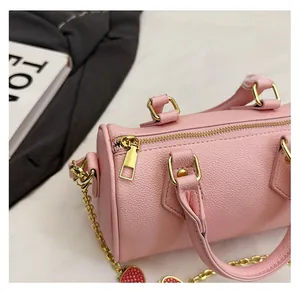 Detail of smooth gold zipper and pink litchi grain leather on the stylish cylinder handbag