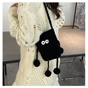 Detail of a handmade black crochet crossbody bag with cute cartoon big eyes and long limbs