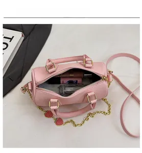 Pink boston bag with litchi texture showing interior space for cosmetics and gold heart chain