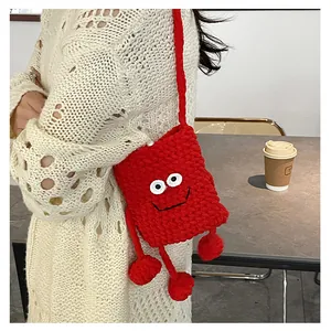 Detail of red crochet mushroom crossbody bag with cartoon eyes and plush pom-poms