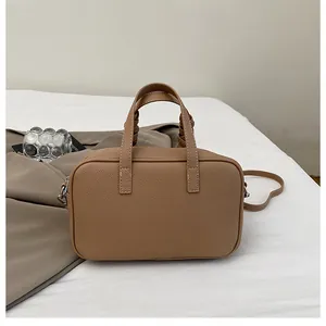 Détail d'un sac à main marron à motif litchi avec fermeture éclair et poignée tissée