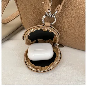 Gros plan sur une mini pochette ronde en cuir à motif lychee avec fermeture éclair et crochet