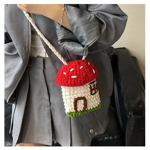 Close-up of a handmade crochet mushroom shoulder bag featuring red and white polka dots