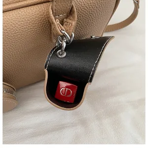 Détail d'un étui à rouge à lèvres en cuir grainé avec anneau en métal et bouton pression