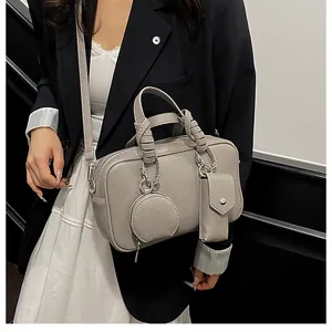 Détail du sac à main gris avec texture litchi et poignées tressées élégantes