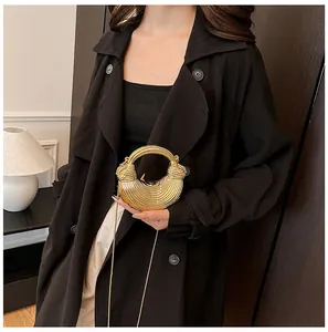 Mini sac demi-lune doré avec texture à rayures et poignée métallique porté par un mannequin