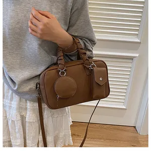 Détail d'un sac Boston en cuir marron avec poignée tressée et mini pochettes de rangement