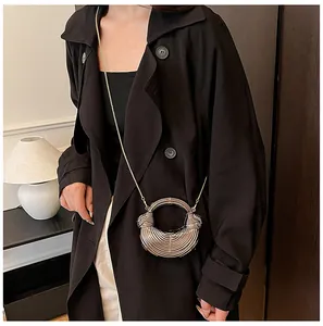 Vue détaillée d'un mini sac demi-lune à chaîne argentée sur un trench-coat noir chic