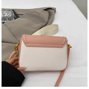 Détail du sac bandoulière bicolore rose et beige avec texture grainée et finitions dorées