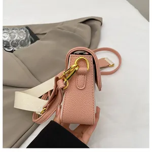 Détail du sac bandoulière en cuir grainé rose avec ferrures dorées et sangle tissée