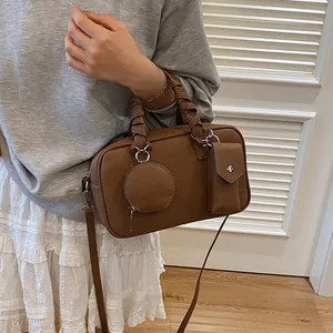 Sac à main marron avec poignée tressée et accessoires porté par un mannequin