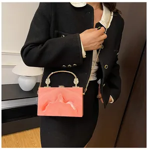 Roze marmeren acryl box tas met goudkleurig handvat en ketting op zwarte kleding