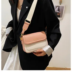 Gros plan d'un sac bandoulière rose et crème avec texture litchi et lettrage doré