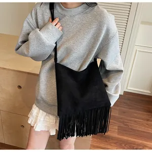 Primer plano del bolso tote de ante negro mate con flecos y detalle de borlas