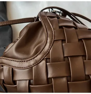 Gros plan sur un sac seau en cuir tressé marron foncé avec de larges bandes et coutures