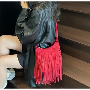 Detailed view of red suede fringe crossbody bag paired with a black leather trench coat