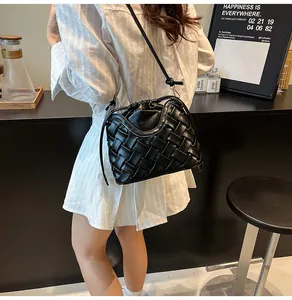 Détail du sac seau noir en cuir tressé avec cordon de serrage dans un décor de café