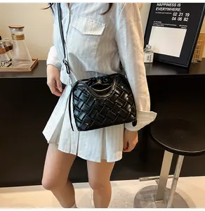 Détail du sac seau noir en cuir tressé avec larges lanières et fermeture à cordon coulissant