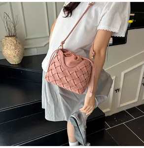 Vue détaillée du sac seau tressé rose poudré avec plis élégants et fine bandoulière