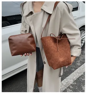 Détail d'un sac seau en daim marron avec sa pochette zippée en cuir assortie