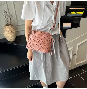 Gros plan d'un sac seau rose tressé porté par un mannequin dans un décor élégant