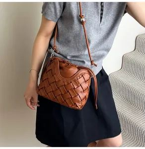 Détail du sac seau marron tressé montrant les ferrures argentées et la boucle à bille