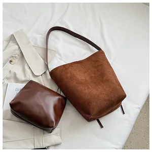 Détail d'un sac seau en daim mat avec pochette assortie sur un fond minimaliste chic
