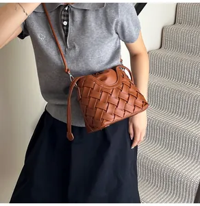 Sac seau tressé marron porté en bandoulière par un mannequin pour un look décontracté