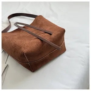 Gros plan sur la texture en daim marron mat et les coutures de ce sac à bandoulière vintage