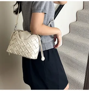 Détail du sac seau tissé blanc crème montrant la texture du cuir et la bandoulière