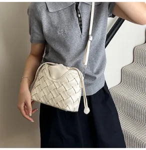 Détail du sac seau tressé crème avec larges lanières en cuir et boucles argent