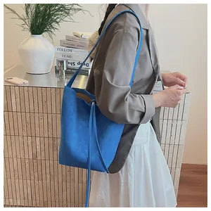 Sac seau en daim bleu porté par un mannequin avec texture et détails de cordon
