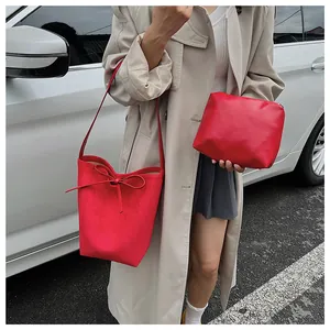 Gros plan d'un sac seau rouge mat avec nœud de serrage et pochette assortie en set