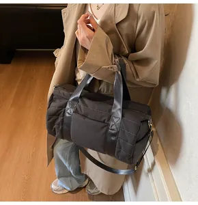 Detail of dark grey quilted cylinder travel bag with detachable strap and golden hardware