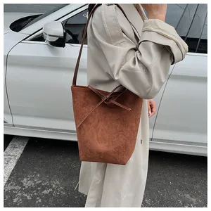 Détail du sac seau marron mat avec nœud papillon et bandoulière sur manteau beige