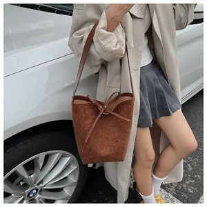 Sac seau chic en daim marron avec nœud décoratif en cuir et intérieur spacieux et élégant