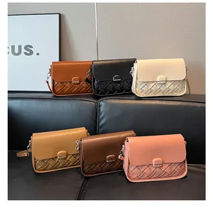 Détail de sacs bandoulière tressés en six couleurs exposés sur un canapé noir