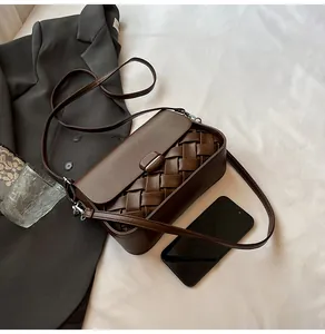 Gros plan sur un sac bandoulière en cuir tressé marron foncé avec des détails argentés