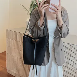Sac seau minimaliste en cuir noir mat avec bandoulière et détails de cordon de serrage